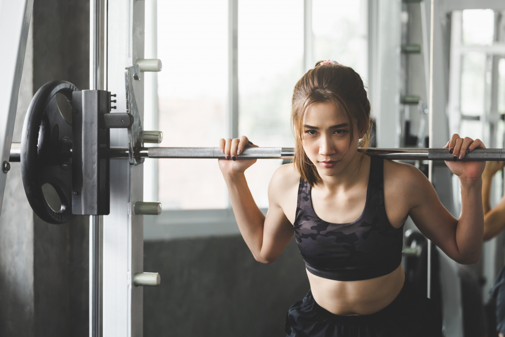 Young woman lifting weights in a home gym.