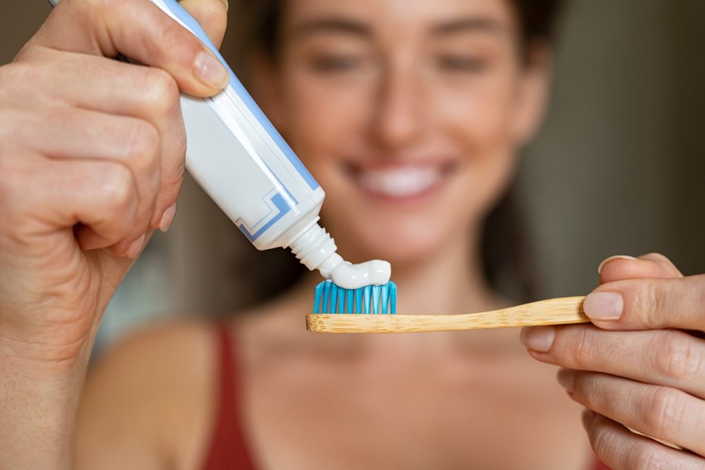 woman applying toothpaste on her toothbrush